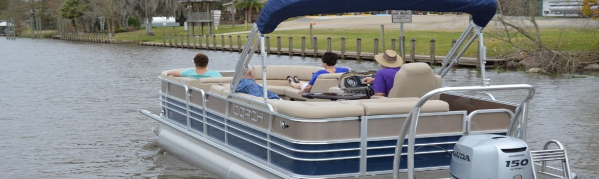 Four individuals floating on a Coach Pontoon near the shore-side. 